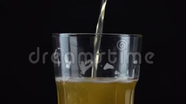 将新鲜和冷的工艺啤酒倒入<strong>一个玻璃</strong>中，上面有白色泡沫在黑色背景上。 流动的泡沫<strong>小</strong>麦或啤酒